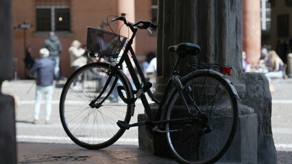 Fototapeta na wymiar Bicycle leaning on old European column. Bike parked outside. Urban alternative transportation