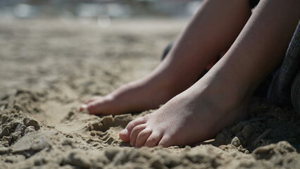 Child feet standing up at beach feeling the sand barefoot. Kid foot walking outside at ocean shore