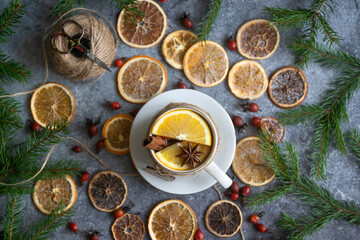 A cup of hot tea with oranges and spices and dried oranges, which are used to make a New Year's garland, 2023 festive background.