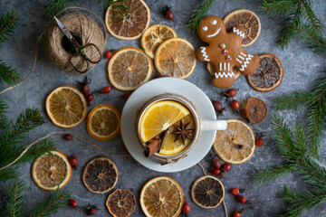 Obraz na płótnie Canvas A cup of hot tea with oranges and spices and dried oranges, which are used to make a New Year's garland, 2023 festive background.
