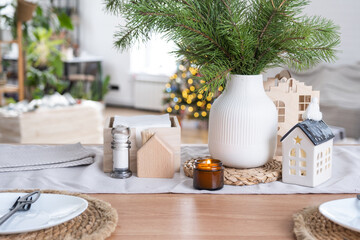 Festive Christmas decor in white kitchen, festive breakfast, white scandi interior. The figure of a cozy house ion the set table. New Year, mood, cozy home. Copy space