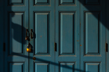 Locked wooden turquoise blue door with some shadow. This represents concept of hiding, secret,...