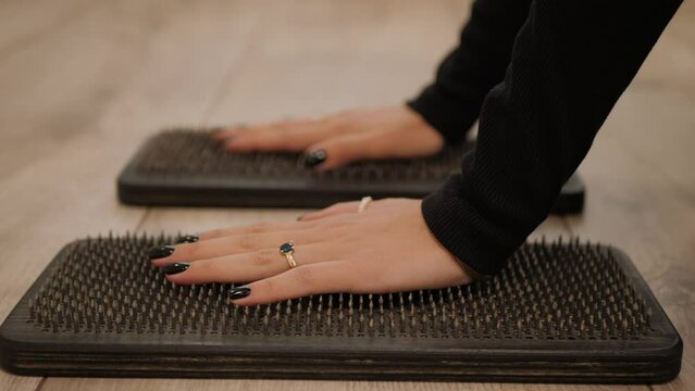 Female palms of hands touch the board with nails. Sadhu board. Women's hands stand on a yoga board