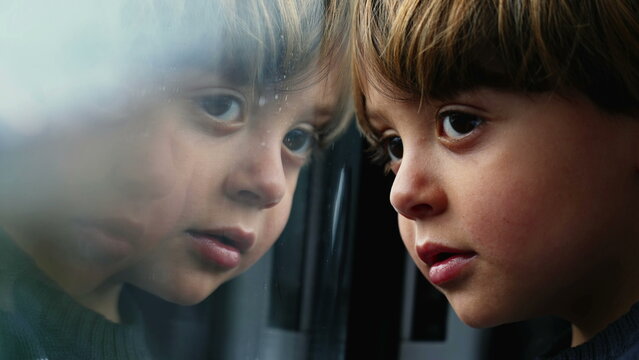One pensive child leaning on train window. Mirror glass reflection of little boy traveling in high speed railroad train. Thoughtful kid watching landscape passing by