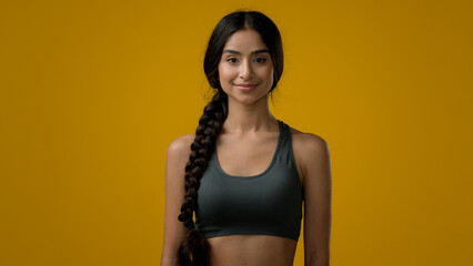 Ethnic 20s woman Indian sport lady smiling multiracial strong slender girl sports trainer yoga runner posing in yellow studio athlete female looking at camera with smile body care healthy lifestyle
