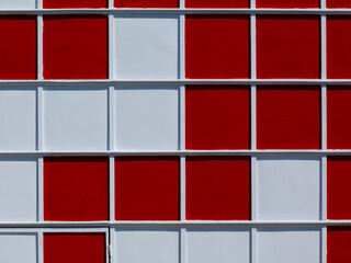 red and white square glass and aluminum curtain wall panels in closeup view. modern architecture. white mullions. elevation detail. mosaic style design. frontal facade clip. - obrazy, fototapety, plakaty