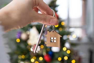 Key to the house in hand on background of Christmas tree. Gift for New Year, Christmas. Building,...