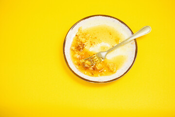 dirty plate with honey and pie crumbs on yellow background