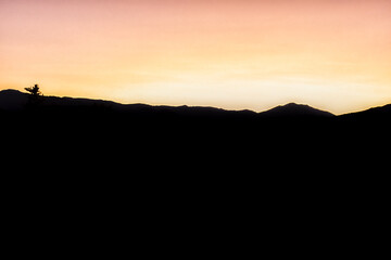 Yellow orange pastel sunset vibrant color in Aspen, Colorado with rocky mountains peak at twilight with mountain ridge dark silhouette