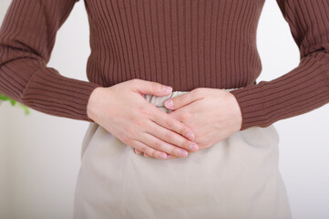 下腹部に手を当てる若い女性