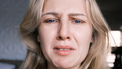 Portrait of crying grieving woman of 30 years. Grimace of sadness with tears in her eyes and...