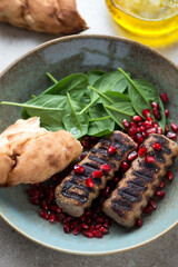 Close-up of barbecued lula kebabs with fresh spinach, pomegranate seeds and lavash, vertical shot, selective focus