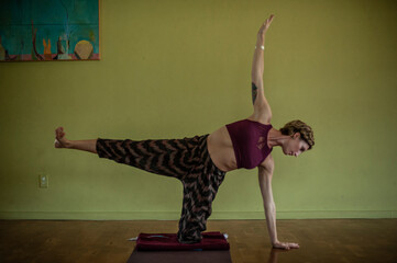 Woman practicing yoga inside of a window lit yoga studio, 