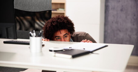 Scared Man Hiding Behind Office Desk