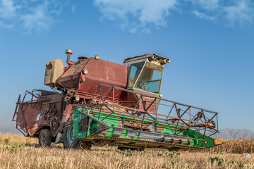 An old harvester works in the field.Collecting safflower by a harvester.