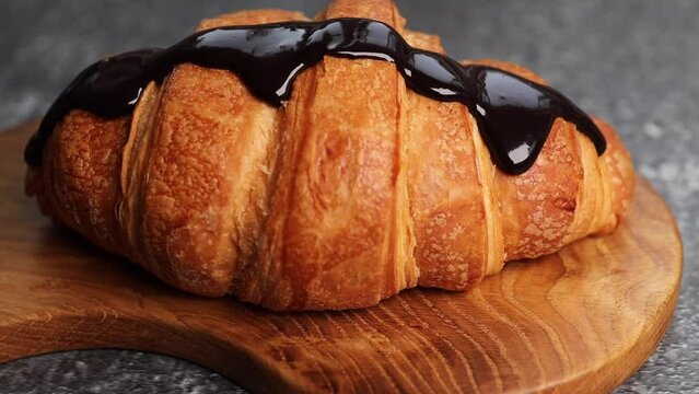 Chocolate flows over the croissant. Fresh French croissant, croissant plan. Dark chocolate is poured onto a French croissant