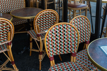 Traditional colorful  wicker chairs and round tables in cafes of Paris