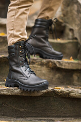 A military man in high black lace-up leather sneakers in a trench