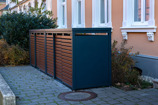 Stylish brown container for trash bins and garbage bins near residential building.