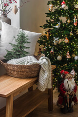 Cozy Christmas house interior. Christmas tree with decor, bench with basket, blankets and pillows