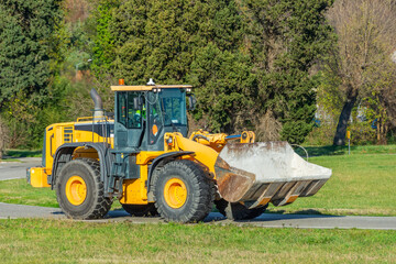 Fototapeta premium Grader and Excavator Construction Equipment on the background of trees rides on the road.