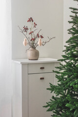 Christmas interior. White wooden chest of drawers with Christmas decor and a Christmas tree in the living room