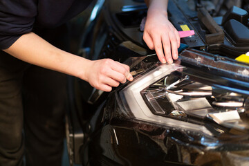 Installation of a protective film on the headlights of the car.Car body protection.