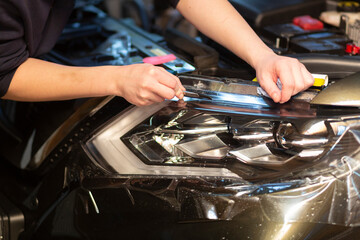 Installation of a protective film on the headlights of the car.Car body protection.