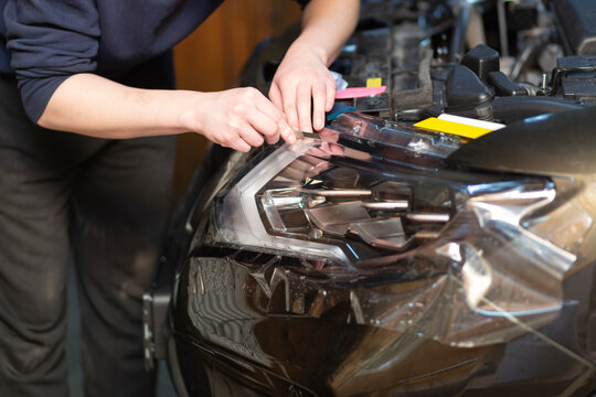 Installation of a protective film on the headlights of the car.Car body protection.