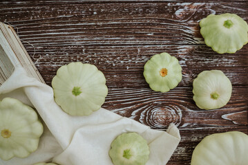 white farm scallop squash, zucchini, pumpkins on a white tablecloth on a brown wooden background