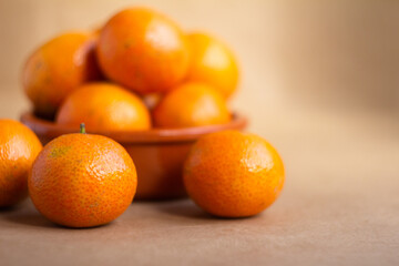 fresh tangerines in a clay plate on a light brown background