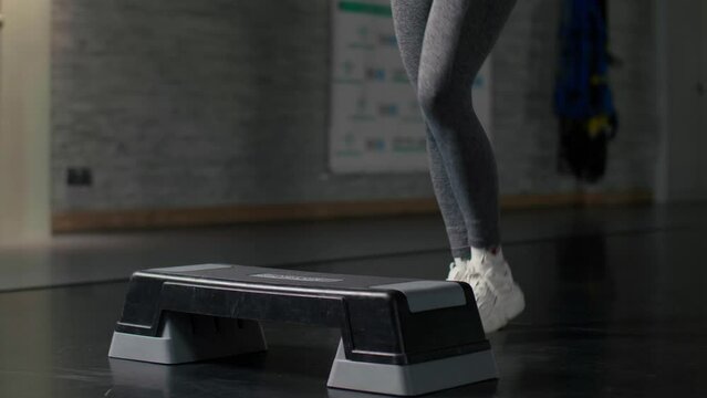 A woman doing exercises on a step platform in slow motion. Active training of female legs in the gym. close up