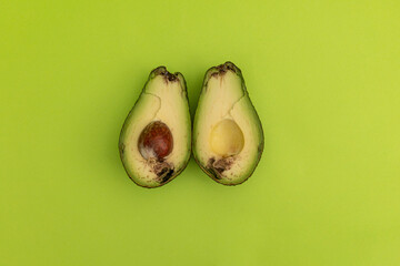Spoiled avocado on green background, monochrome