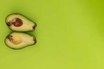 Spoiled avocado on green background, monochrome