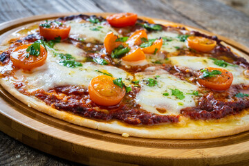 Circle with mozzarella, salami and cherry tomatoes on wooden table
