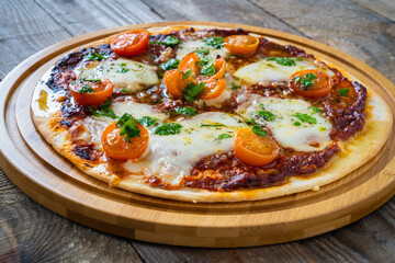 Circle with mozzarella, salami and cherry tomatoes on wooden table
