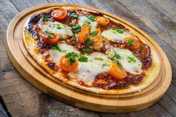 Circle with mozzarella, salami and cherry tomatoes on wooden table
