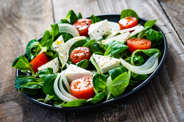Fresh vegetable salad with feta cheese on wooden table
