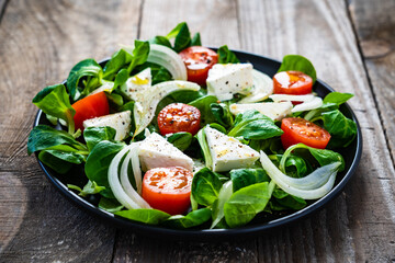 Fresh vegetable salad with feta cheese on wooden table
