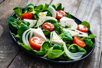 Fresh vegetable salad with feta cheese on wooden table
