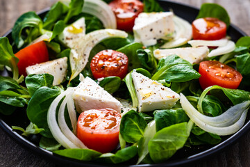 Fresh vegetable salad with feta cheese on wooden table
