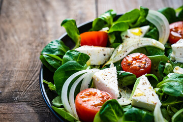 Fresh vegetable salad with feta cheese on wooden table
