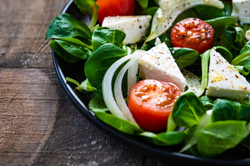 Fresh vegetable salad with feta cheese on wooden table

