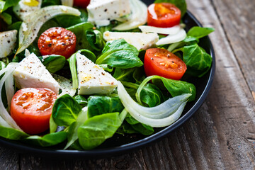 Fresh vegetable salad with feta cheese on wooden table
