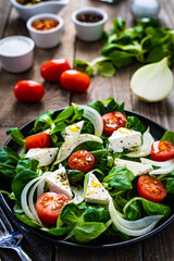 Fresh vegetable salad with feta cheese on wooden table
