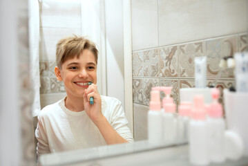 Smiling teen boy brushing teeth in bathroom. Beautiful healthy child at home brush teeth, looking...