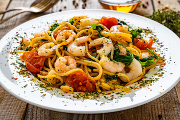 Spaghetti with prawns and spinach on wooden table