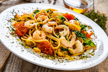 Spaghetti with prawns and spinach on wooden table