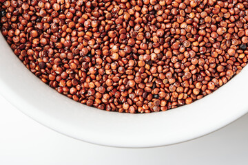 Red quinoa seeds in a white bowl.