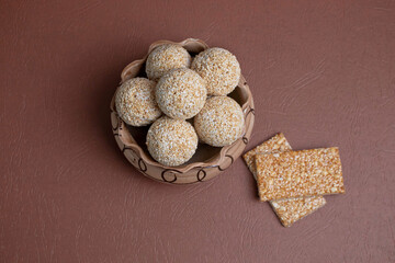 The indian sesame sweet or tilgul laddu, made up of jaggery and sesame seeds, indian sweet for Makar Sankranti festival, pile or stacked on black background, closeup showing texture, selective focus